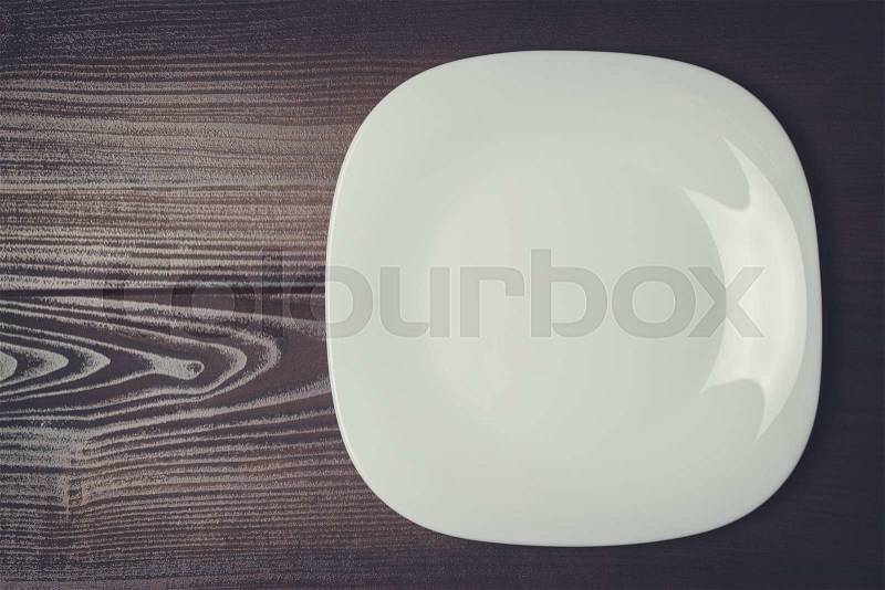 White square plate on the wooden brown table, stock photo