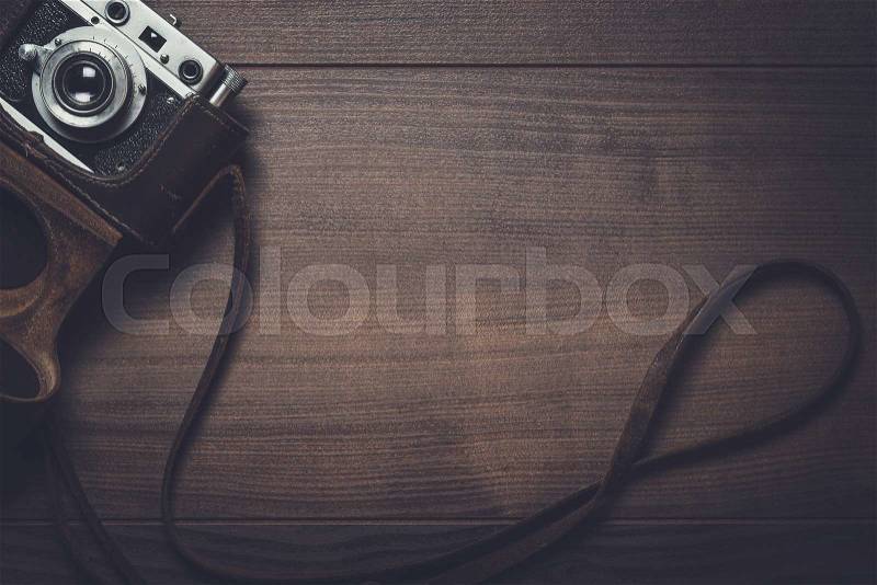 Wooden background with retro still camera in case, stock photo