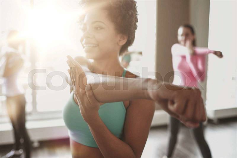 Fitness, sport, dance, people and lifestyle concept - close up of smiling african american woman with group of women dancing zumba in gym or studio, stock photo