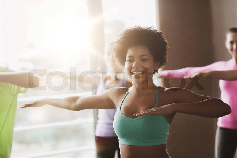 Fitness, sport, dance and lifestyle concept - group of smiling people with coach dancing zumba in gym or studio, stock photo
