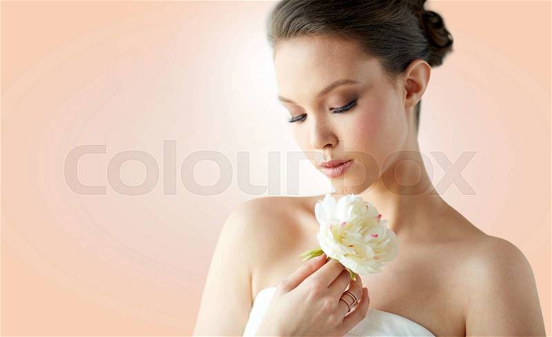 Beauty, jewelry, people and luxury concept - beautiful asian woman or bride in white dress with peony flower and golden ring over beige background, stock photo