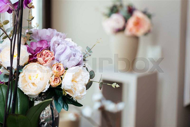 Bouquets of beautiful flowers standing in vases in the room, stock photo