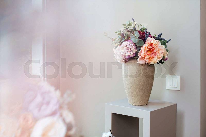 Vase with beautiful fresh flowers standing on small table , stock photo