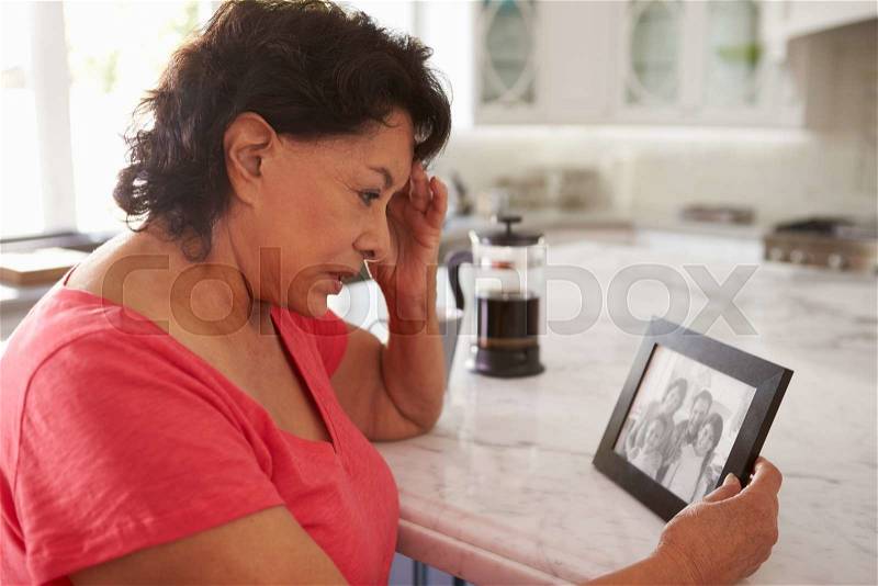 Senior Hispanic Woman At Home Looking At Old Photograph, stock photo