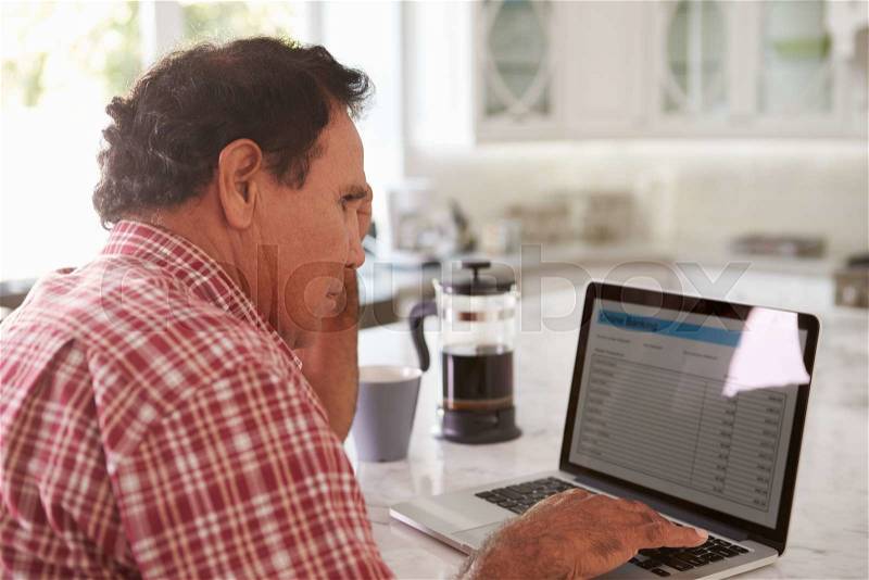Confused Senior Hispanic Man Sitting At Home Using Laptop, stock photo