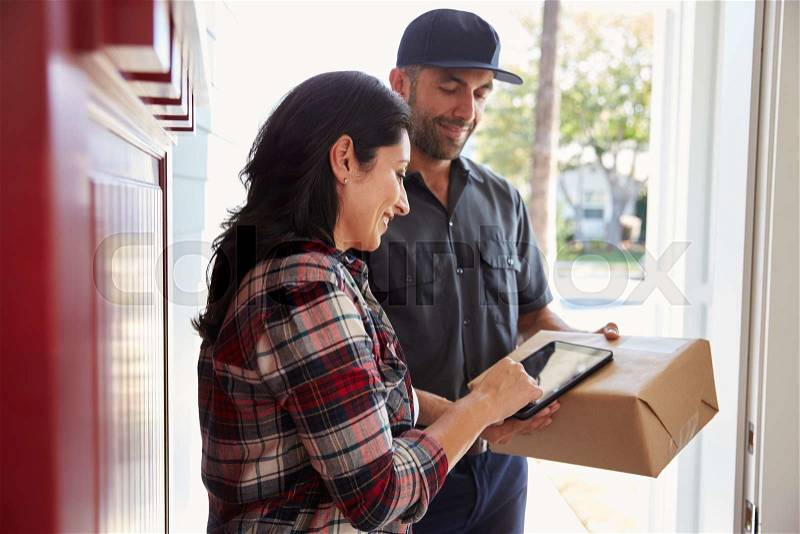 Woman Signing For Package From Courier At Home, stock photo