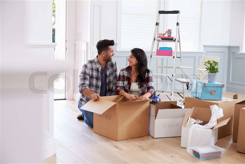 Hispanic Couple Moving Into New Home And Unpacking Boxes, stock photo