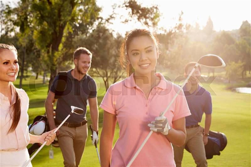 Group Of Golfers Walking Along Fairway Carrying Golf Bags, stock photo