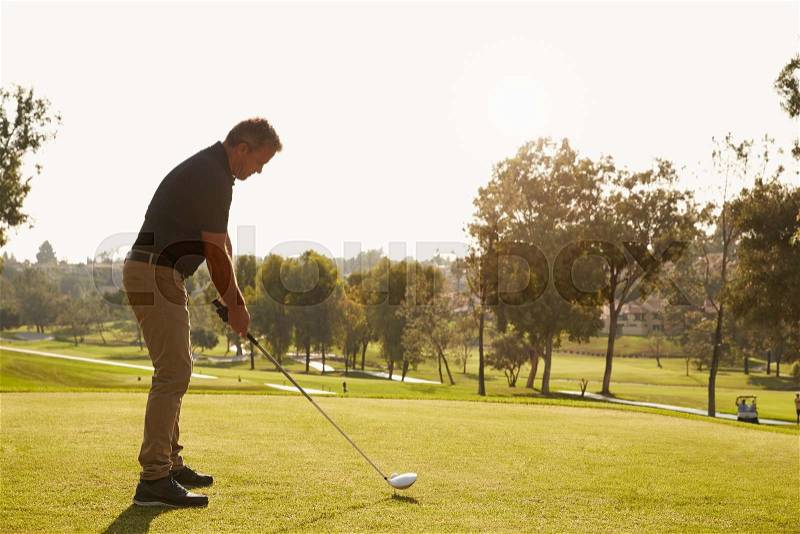 Male Golfer Lining Up Tee Shot On Golf Course, stock photo
