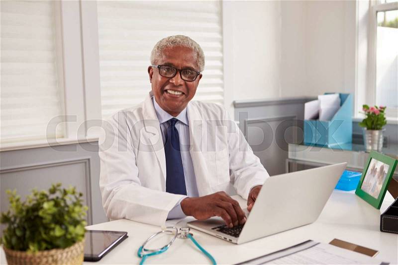 Senior black male doctor at an office desk looking to camera, stock photo