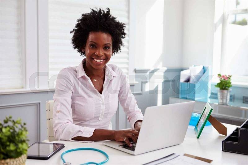 Black female doctor at work in an office, looking to camera, stock photo