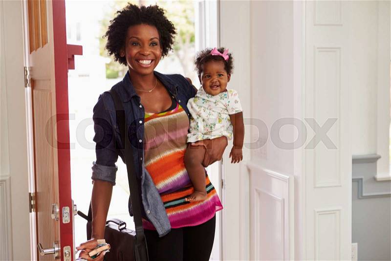Young black woman holding child arriving home, stock photo