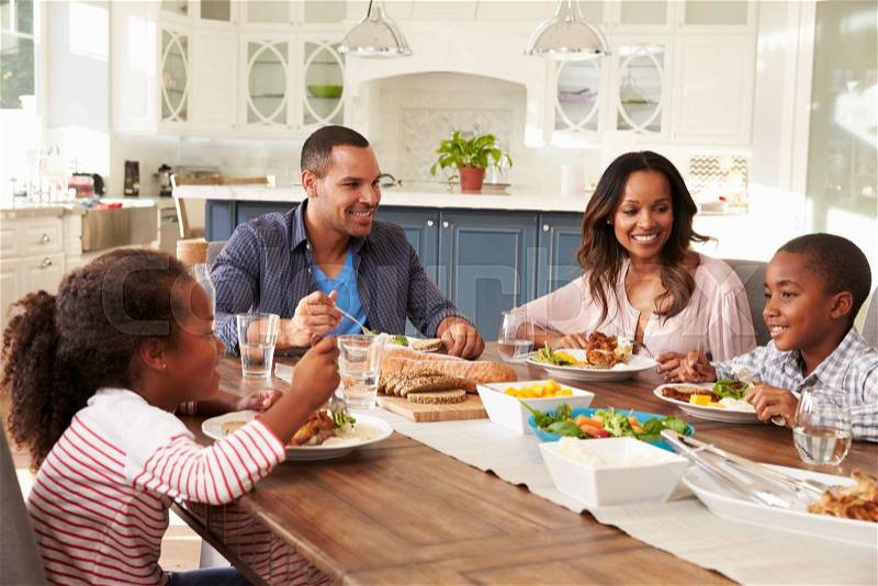 Parents and their two children eating at kitchen table, stock photo