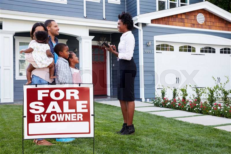 Estate agent and family outside house with a ‘for sale’ sign, stock photo