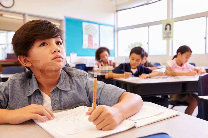 Asian schoolboy in elementary school class looking at board, stock photo