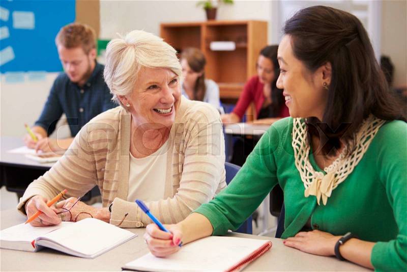 Teacher and student sit together at an adult education class, stock photo
