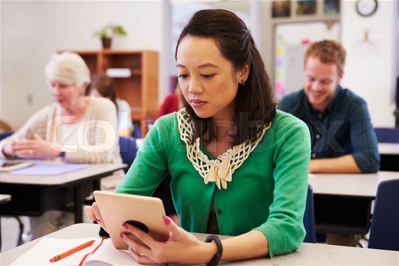 Asian woman using tablet computer in adult education class, stock photo