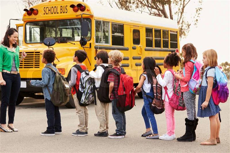 Teacher and a group of elementary school kids at a bus stop, stock photo