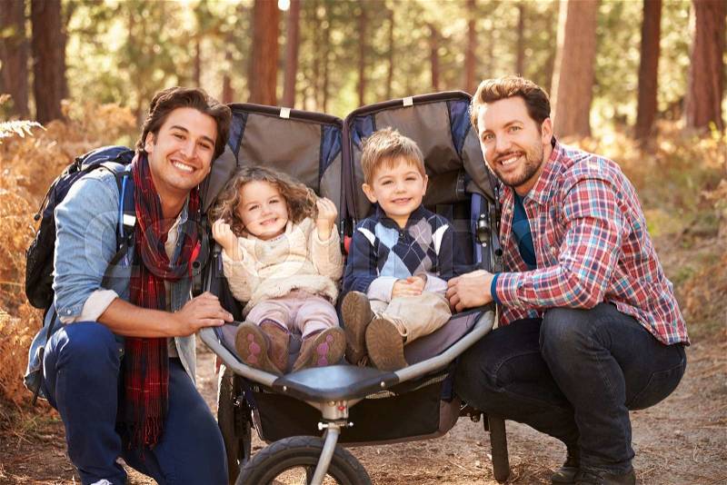 Gay Male Couple Pushing Children In Buggy Through Woods, stock photo