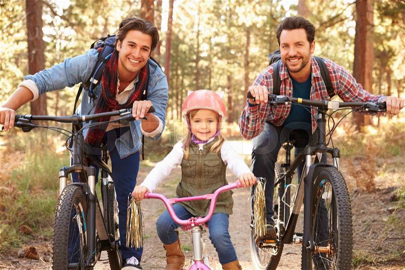 Gay Male Couple With Daughter Cycling Through Fall Woodland, stock photo