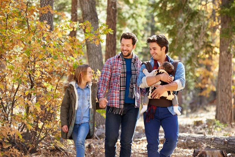 Gay Male Couple With Children Walking Through Fall Woodland, stock photo