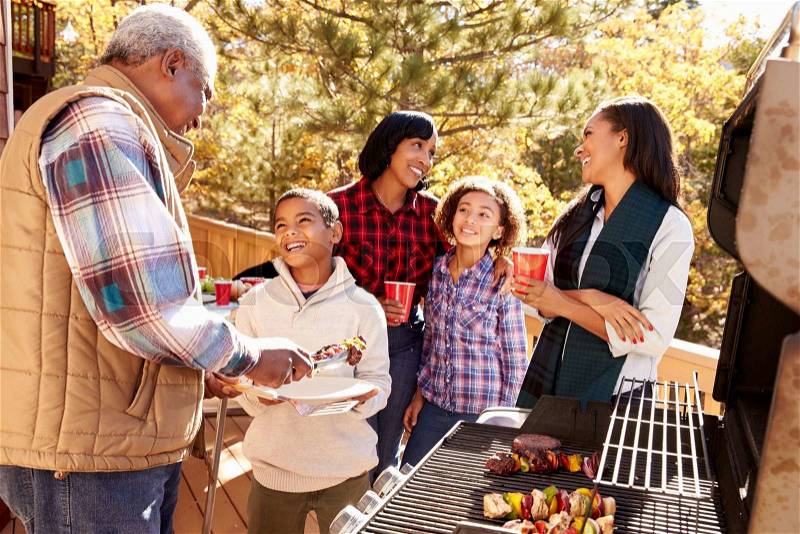 Grandparents With Children Enjoying Outdoor Barbecue, stock photo
