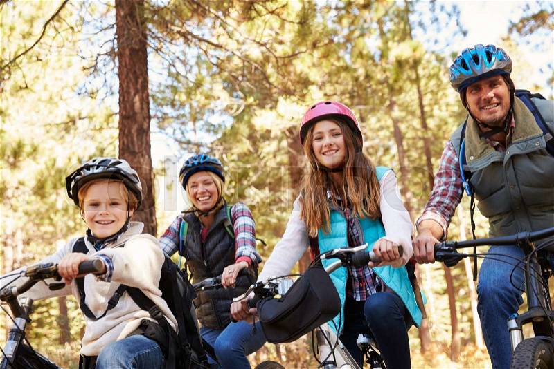 Family mountain biking in a forest, looking to camera, stock photo