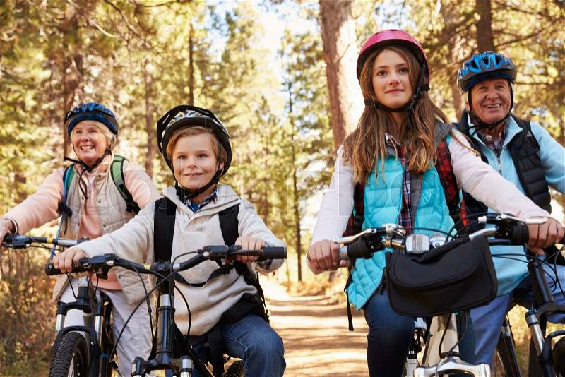 Grandparents and grandkids cycling on forest trail, close up, stock photo