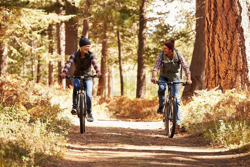 Couple mountain biking through forest, California, stock photo