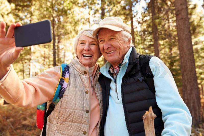 Senior couple on hike in a forest taking a selfie, stock photo