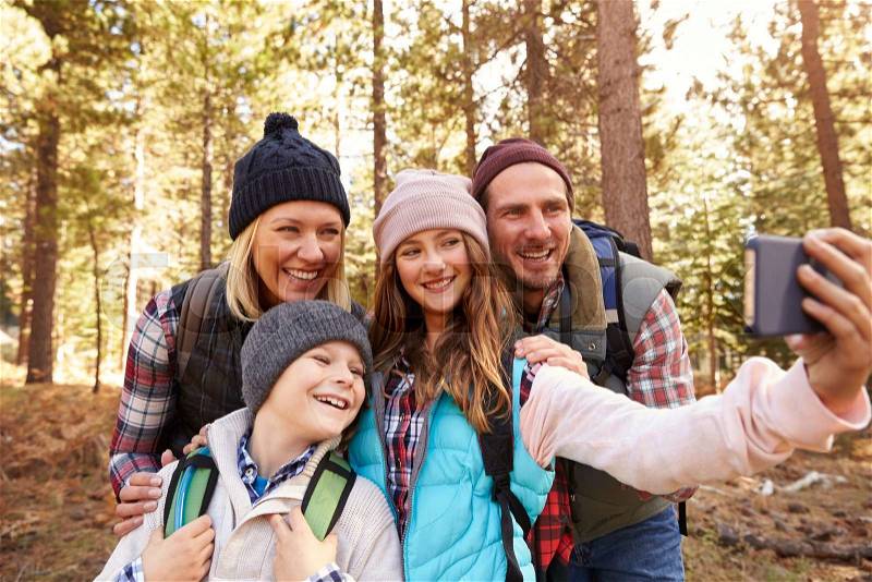 Family on hike in a forest taking selfie group portrait, stock photo
