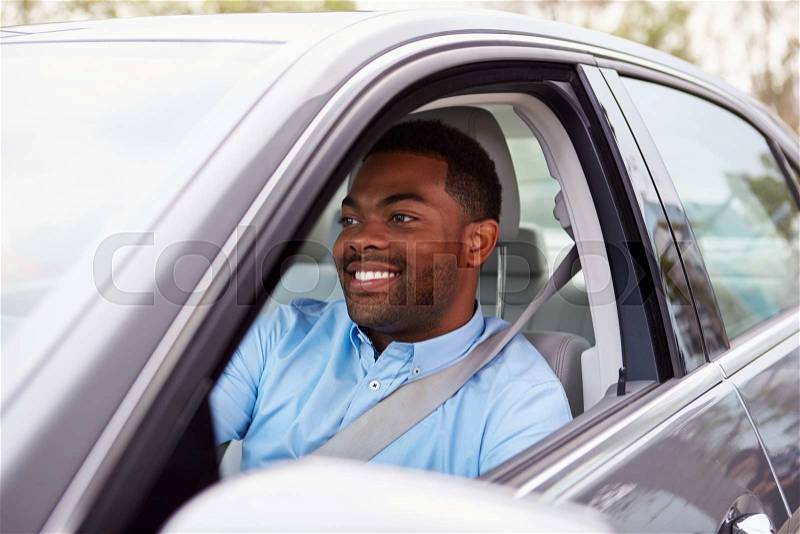 Happy African American male driver in car, stock photo