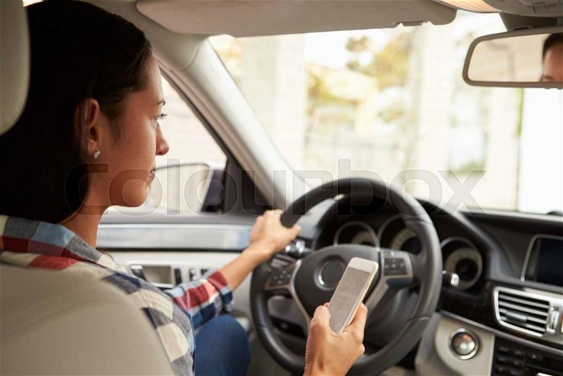 In car view of Hispanic female driver using phone, stock photo