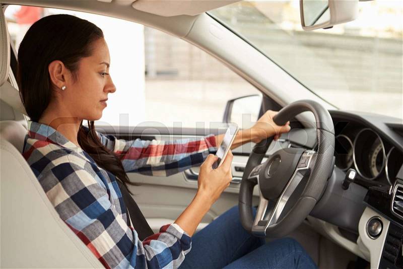 In car view of Hispanic female driver using phone, stock photo