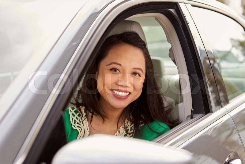 Female Asian driver looking to camera through side window, stock photo