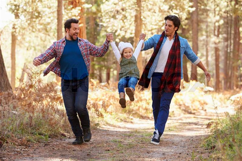Gay Male Couple With Daughter Walking Through Fall Woodland, stock photo