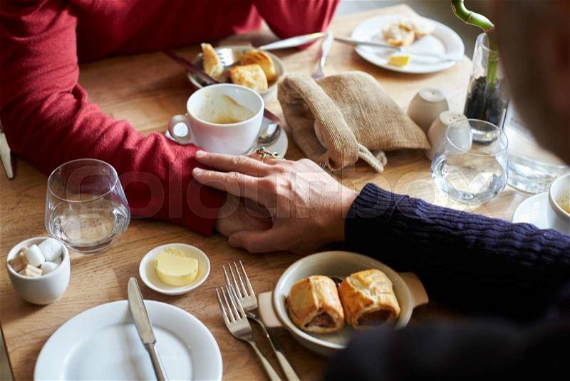 Male couple holding hands at restaurant table, hands detail, stock photo