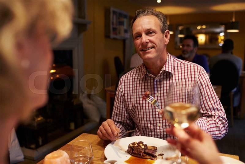 Senior couple eating meal in a restaurant, over-shoulder view, stock photo
