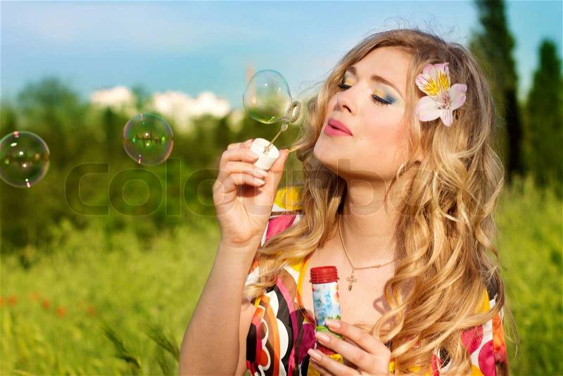 Young girl makes soap bubble, stock photo