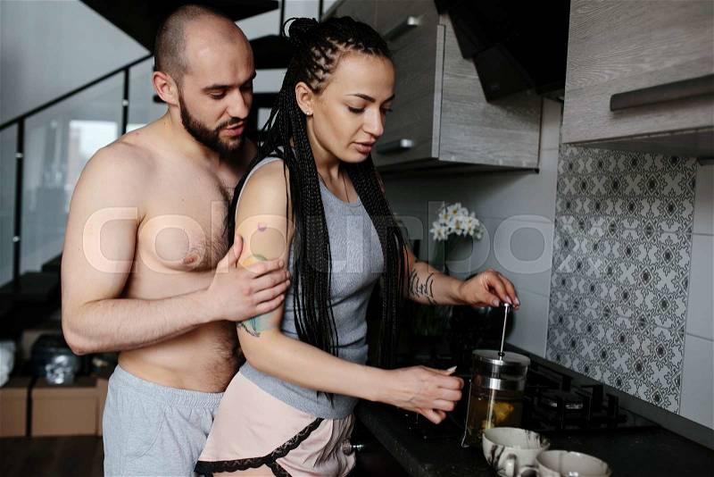 Man and woman together making tea in the kitchen, stock photo