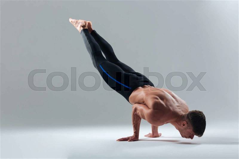 Fitness man doing balance pose isolated on a white background, stock photo