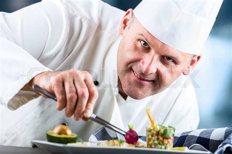 Chef. Chef cooking.Chef decorating dish. Chef preparing a meal. Chef in hotel or restaurant kitchen prepares decorating dish with tweezers. Chef cooking, only hands, stock photo