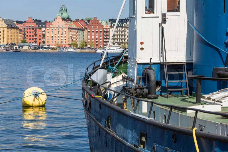 Old city buildings and old boats on water under blue sky in Stockholm, Sweden, stock photo