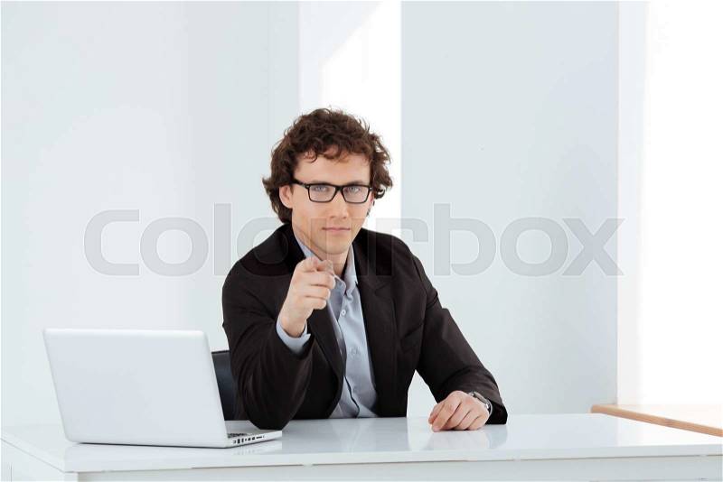 Serious businessman pointing finger at camera in office, stock photo