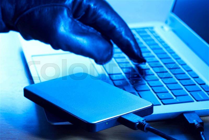 Cyber Criminal Downloading Data Onto Portable Hard Drive, stock photo