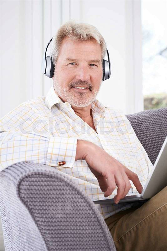 Mature Man Streams Music From Laptop To Wireless Headphones, stock photo