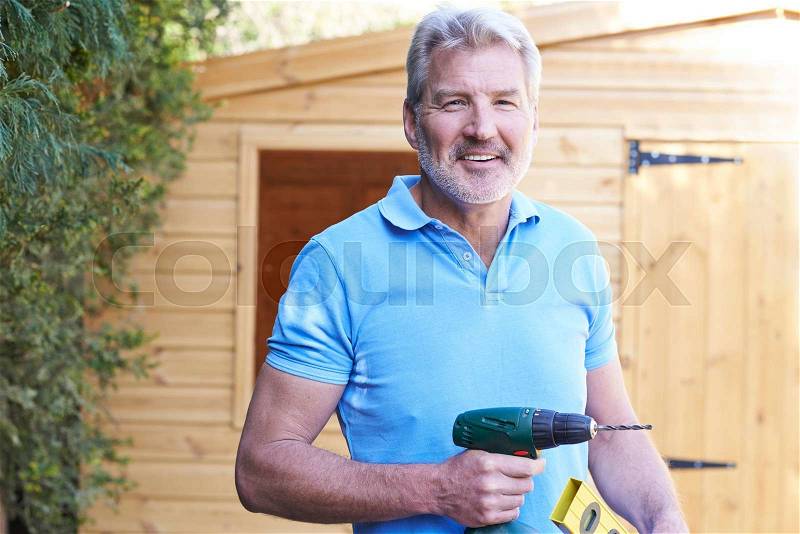 Handyman Standing Outside Garden Shed With Tools, stock photo