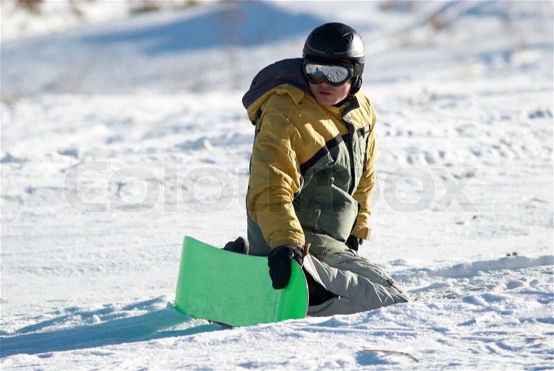 Snowboarder sits on slope in expectation of, stock photo