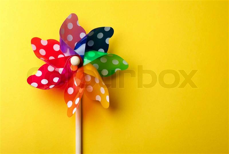 Childrens colorful windmill toy isolated on yellow background, stock photo