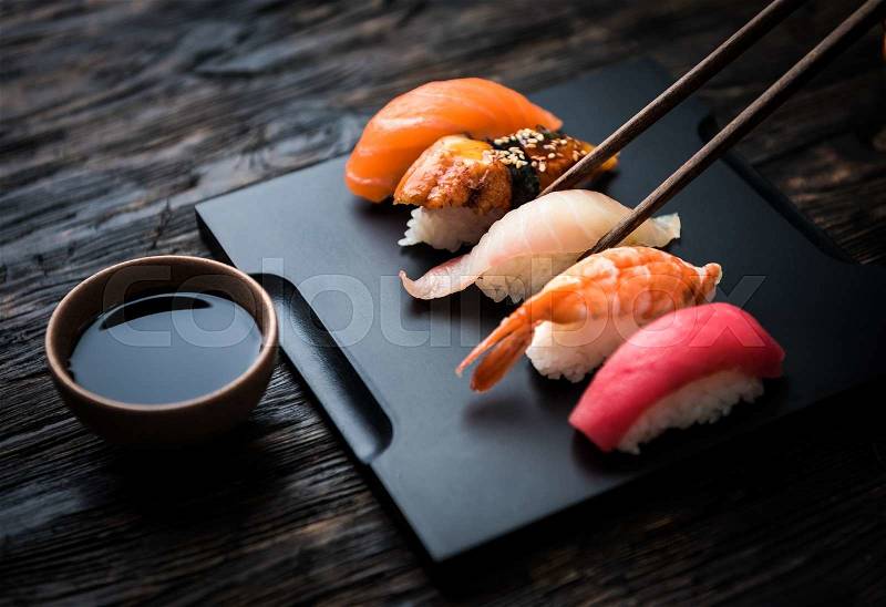 Close up of sashimi sushi set with chopsticks and soy on black background, stock photo